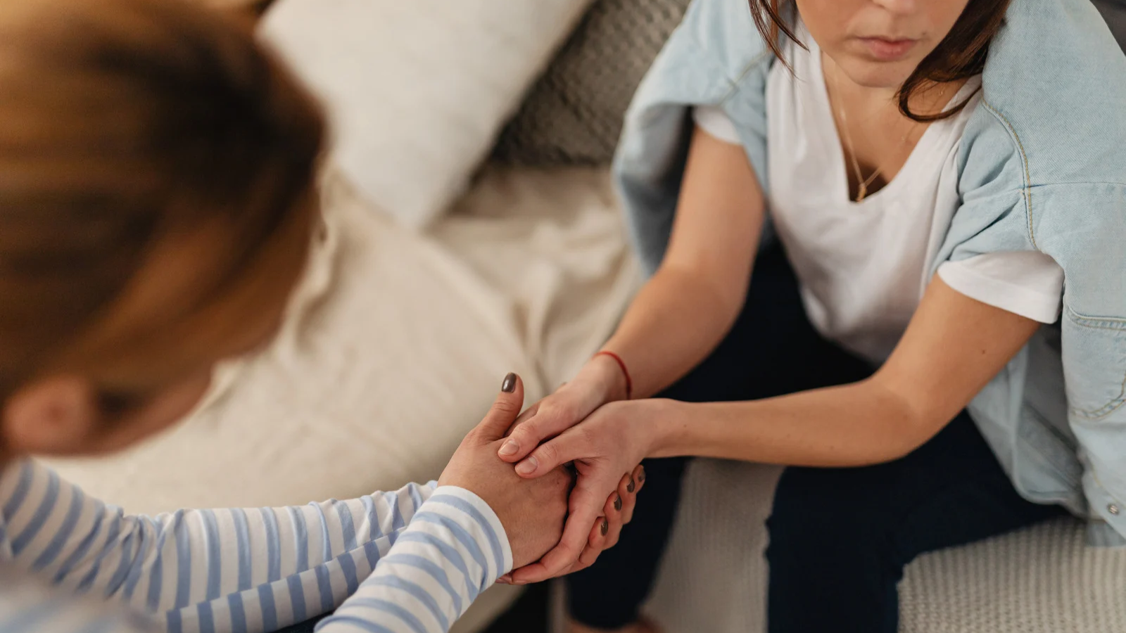 Dos mujeres cogiéndose de las manos en señal de apoyo