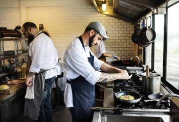 3 profesionales de la hostería trabajando en una cocina.