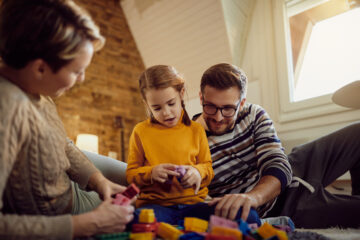 Padre y madre jugando con bloques con su hija.